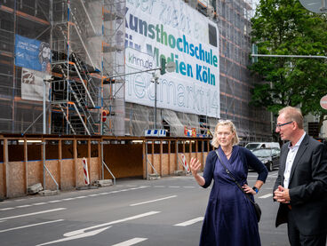 Ministerialrätin Susanne Graap mit Dr. Oliver Herrmann vor eingerüstetem Hauptgebäude